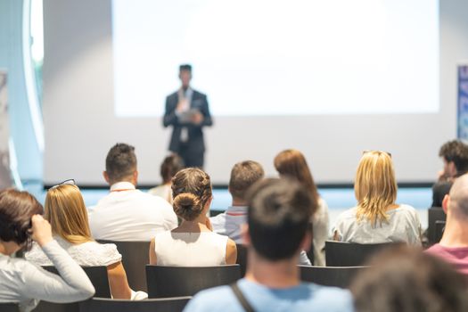 Male speaker giving a talk in conference hall at business event. Audience at the conference hall. Business and Entrepreneurship concept. Focus on unrecognizable people in audience.