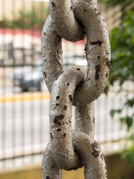 Close up of rusty chain links in foreground, with grid on background