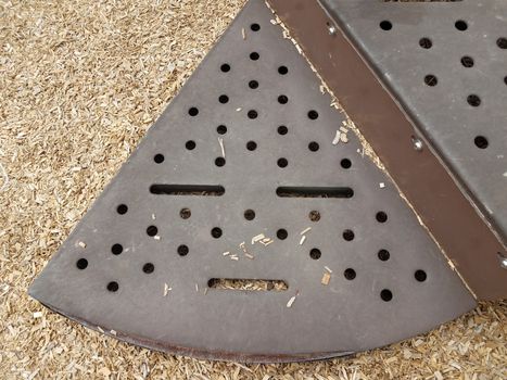 brown metal step on play stucture with holes that looks like a face