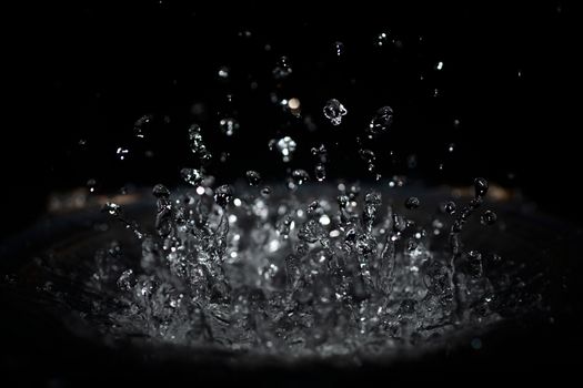 The splash of water drops in loudspeaker on black background. Perpetual motion, music and power concept.