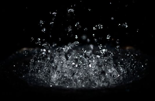 The splash of water drops in loudspeaker on black background. Perpetual motion, music and power concept.