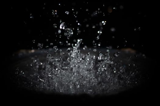 The splash of water drops in loudspeaker on black background. Perpetual motion, music and power concept.