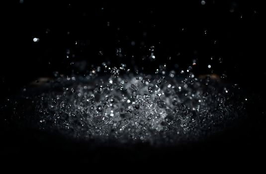 The splash of water drops in loudspeaker on black background. Perpetual motion, music and power concept.