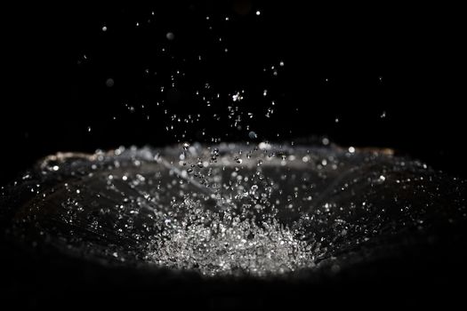 The splash of water drops in loudspeaker on black background. Perpetual motion, music and power concept.