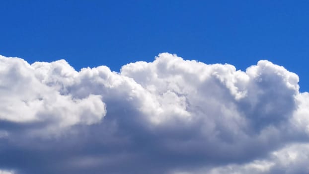 White cumulus clouds against a blue sky.