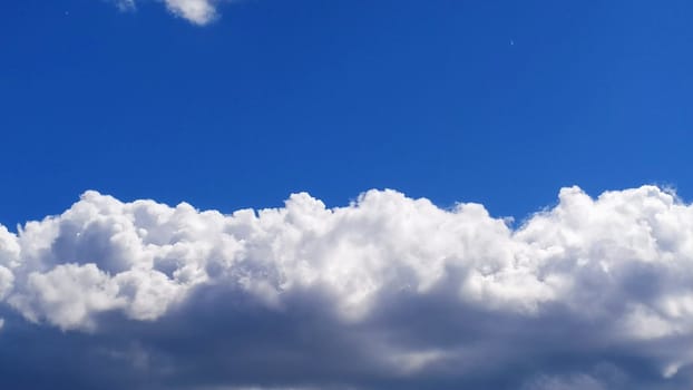 White cumulus clouds against a blue sky.