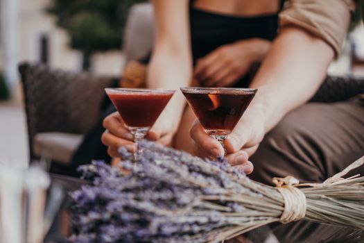 Romantic date. lovers holding hands at the table. Cocktail on the background. Love concept. Dried lavender bunches on the background
