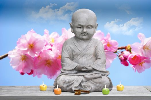 Buddha stone statue child background cherry blossom lighted candles and incense