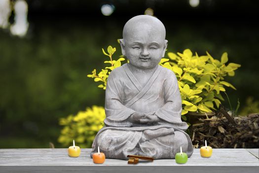 Buddha stone statue child background blur lit candles and incense