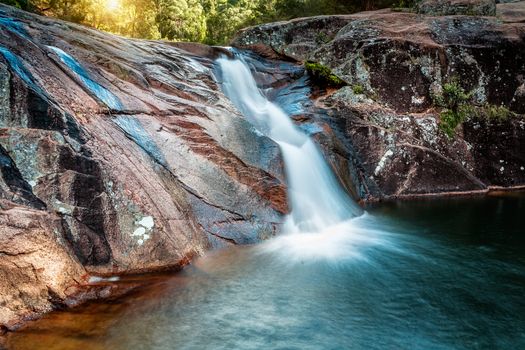 A lush slip slide waterfall into a swimming hole in Australian bushland