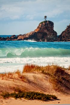 Early sunlight on One tree rock as waves crash on the shoreline