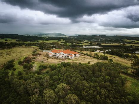 Storm clouds loom heavy over an abandoned mansion that now sits derelect in rural countryside