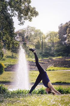 vertical photo of a young sports woman doing meditation yoga exercises and relaxing outdoors in the park, modern healthy lifestyle and sport concept