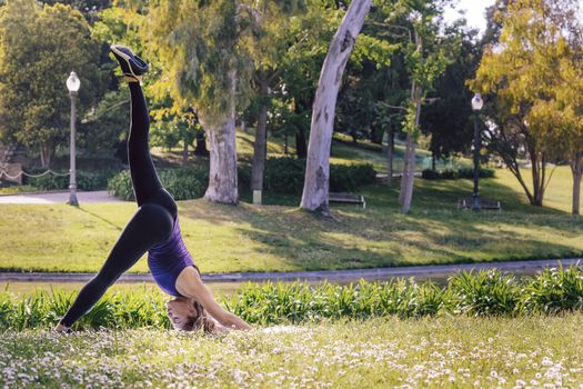 young sports woman doing meditation yoga balancing exercises and relaxing outdoors in the park, modern healthy lifestyle and sport concept