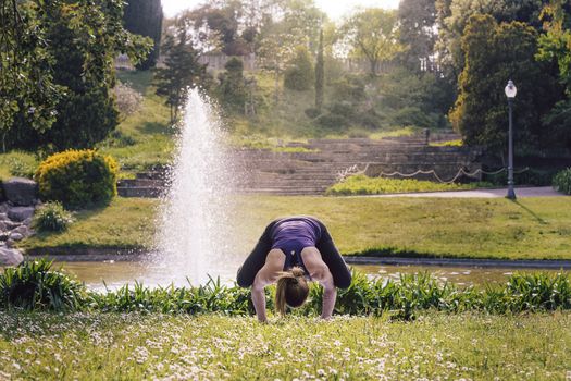 strong and young sports woman doing meditation yoga balancing exercises and relaxing outdoors in the park, modern healthy lifestyle and sport concept