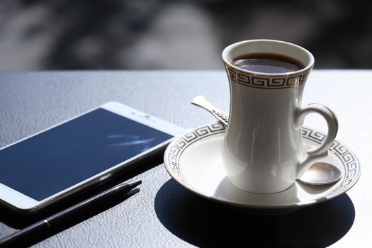 Work day beginning. Cup of black coffee near smartphone