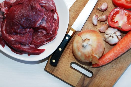 Portion of raw beef meat for cooking near vegetables