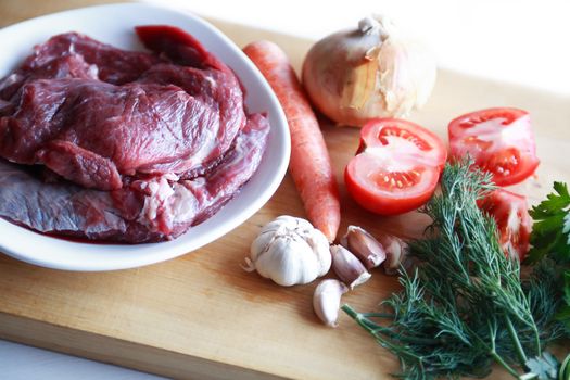 Portion of raw beef meat for cooking near vegetables