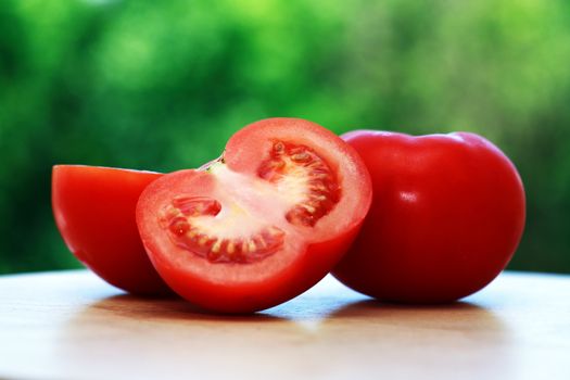 Few red ripe tomatoes against morning nature background