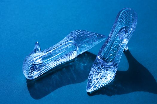 Pair of nice glass slippers on blue background with shadow