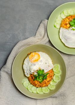 top view of fried rice served fried eggs with fresh cucumber