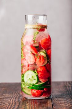 Bottle of Flavored Water with Fresh Strawberry, Sliced Cucumber and Springs of Thyme. Vertical Orientation.