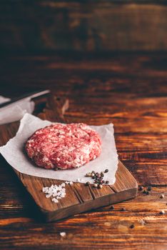 Raw Beef Patty with Spices on Cutting Board for Burger. Vertical Orientation with Copy Space.