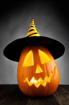 Jack O Lantern Halloween pumpkin with witches hat on wooden background