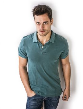 Handsome young man in green shirt and jeans posing isolated on white background in studio,
