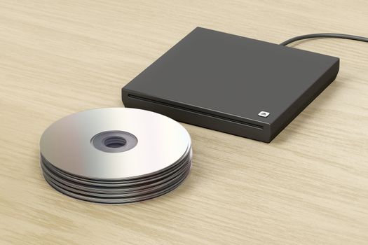 Stack of optical discs and external slot-loading optical drive on wood table