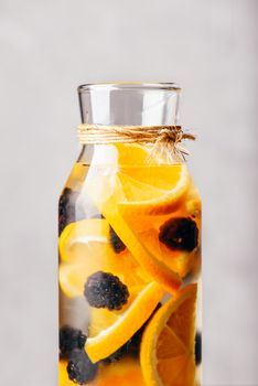 Part of Bottle of Detox Water Infused with Sliced Raw Orange and Fresh Blackberry.