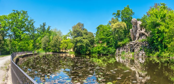 The majestic big statue of Colosso dell Appennino giant statue and pond in public gardens of Pratolino near Florence in Italy - panoramic wide shot .