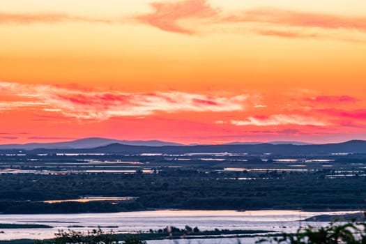 Sunset on the embankment of the Amur river in Khabarovsk. The sun set over the horizon. The embankment is lit by lanterns.