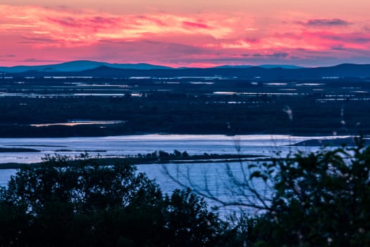 Sunset on the embankment of the Amur river in Khabarovsk. The sun set over the horizon. The embankment is lit by lanterns.