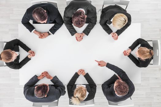 Business, people and team work concept - close up of creative team sitting at table and pointing finger to blank copy space for text