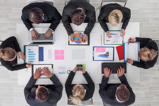 Business people work with statistics documents with tables and diagrams sitting around the table