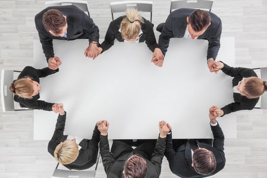 Business team holding hands sitting around the table, top view , copy space for text