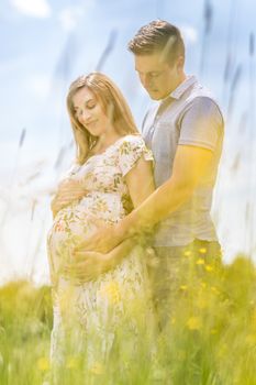 Young happy pregnant couple hugging in nature. Concept of love, relationship, care, marriage, family creation, pregnancy, parenting