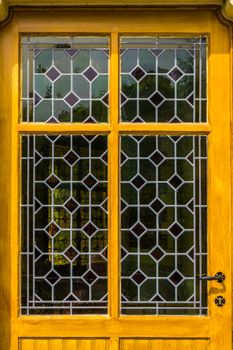 wooden yellow door with tainted glass pattern in diverse colors, Vintage background