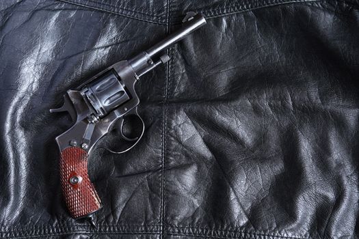 Old revolver on black leather background with free space