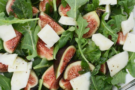 Wedges of fresh figs, chunks of pecorino cheese and green rocket leaves in a fresh summer salad