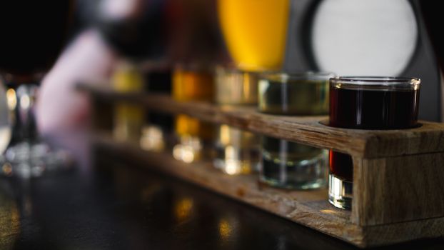 Multicolored transparent cocktails, a set of shots in one row, six servings on a wooden stand, substrate. Drink for the menu restaurant, bar, cafe