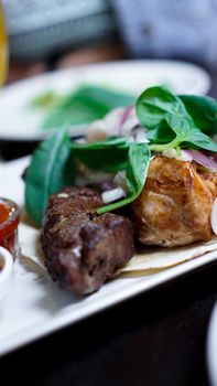 Pieces of meat with onions on skewers kebab. Serve with sauce on a white plate.