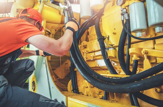 Caucasian Professional Mechanic Fixing Bulldozer Engine Inside Heavy Equipment Repair Shop.