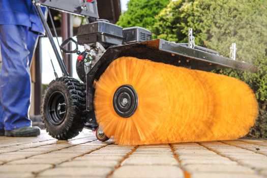 Driveway Power Brushing. Worker with Brick Cleaning Machine. Industrial Theme.