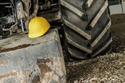 Industrial Safety Concept with Yellow Hard Hat and the Heavy Construction Equipment.