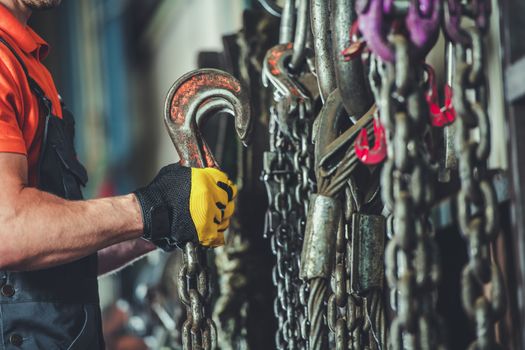 Heavy Equipment Support Chains and Hooks. Worker Looking For the Right Hauling Chain.