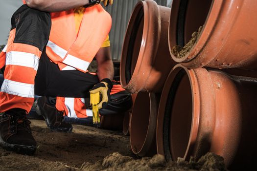 Sewage Pipeline Construction Project. Worker Preparing Plastic Pipes For Installation. Industrial Theme.