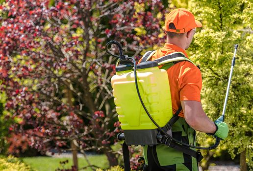 Agriculture Theme. Seasonal Insecticide Work. Caucasian Garden Worker with a Substance Used for Killing Insects Spraying Plants.

