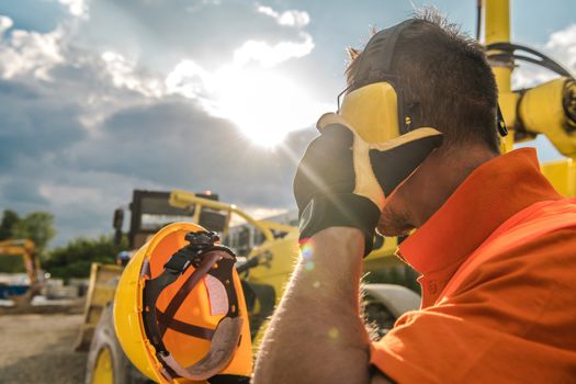 Construction Noise. Heavy Machinery Operator with Noise Reduction Headphones on His Head. Industrial Concept.